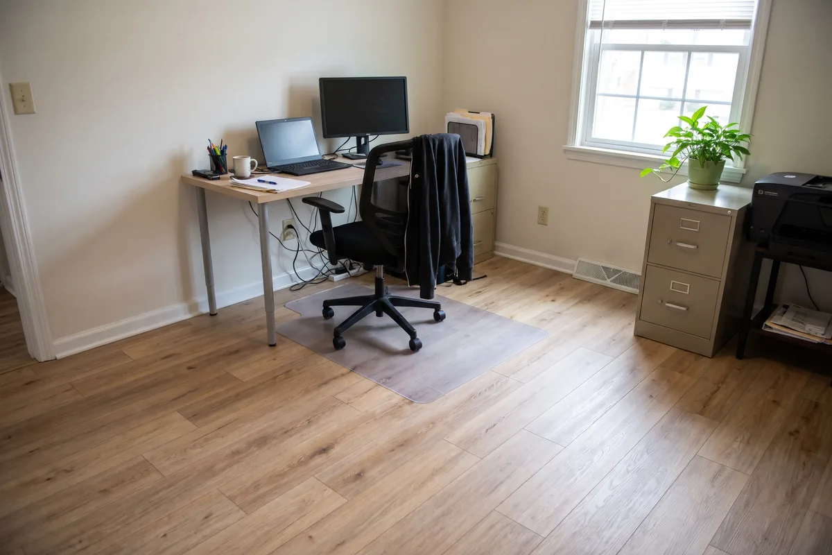 Light oak-look vinyl plank in a home office with a chair mat under the desk chair
