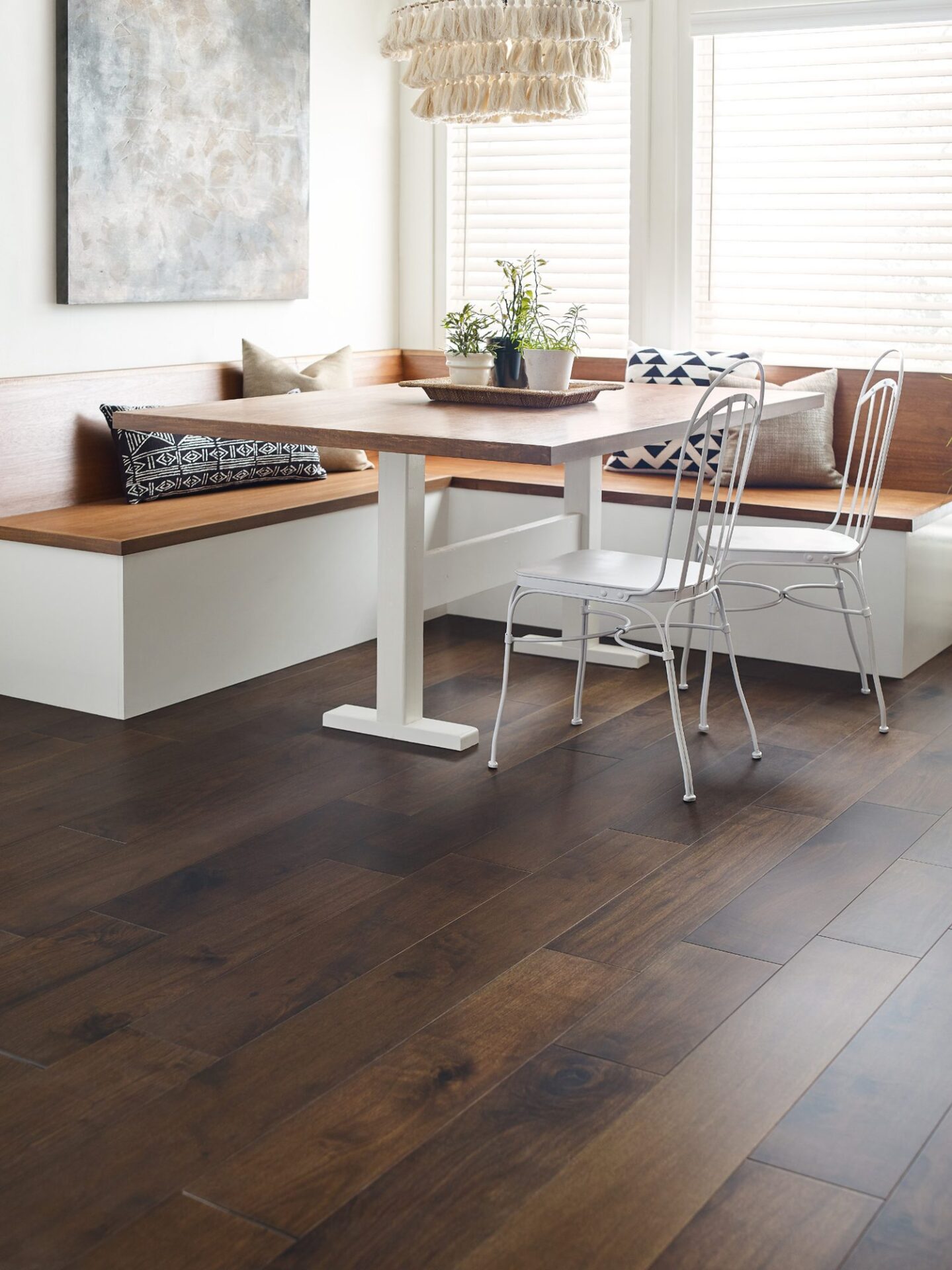 Breakfast nook with dark walnut hardwood floor, a built-in bench, wood table and white metal chairs under a window