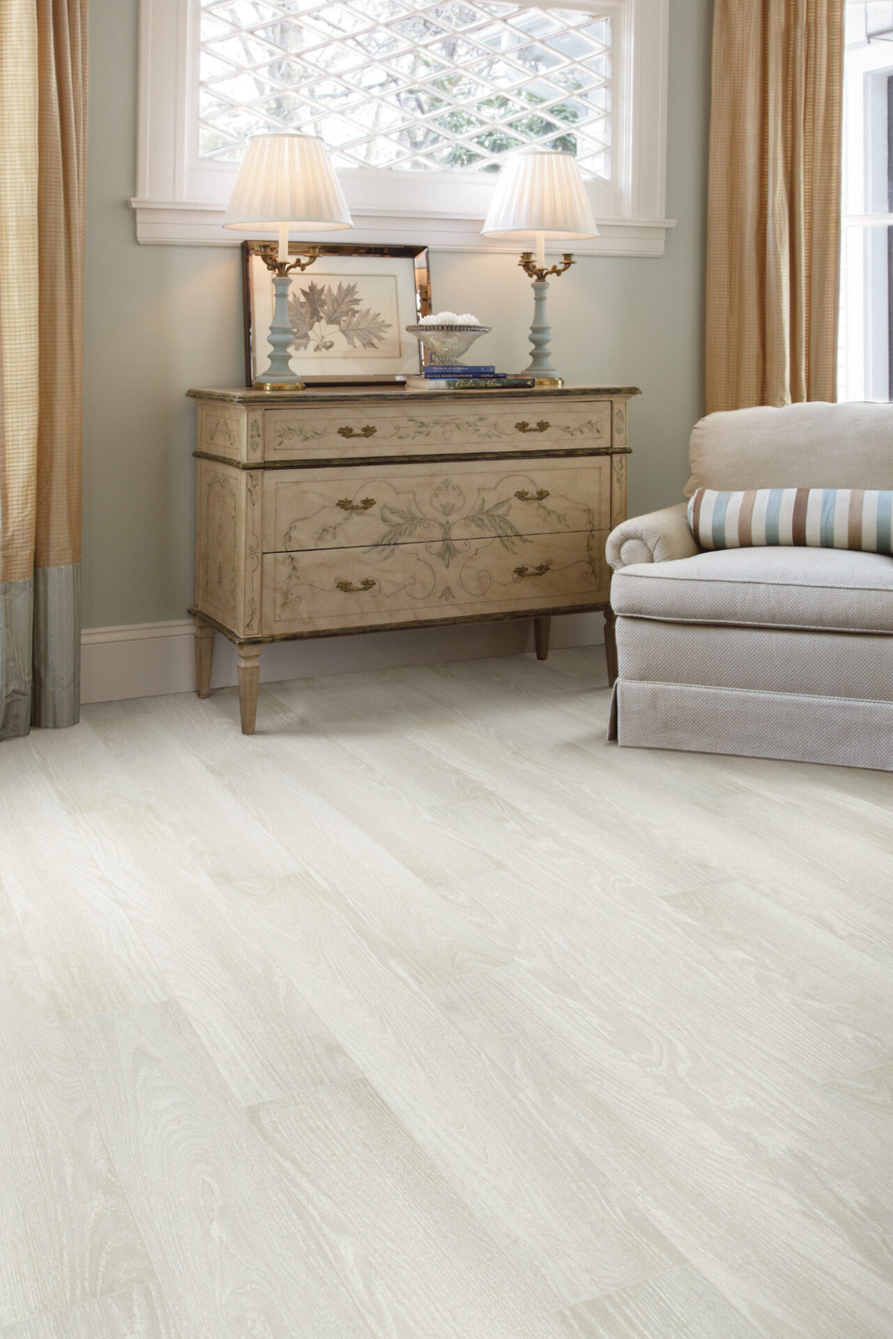 Whitewashed oak-look laminate flooring in a sitting room with a dresser, lamps and armchair