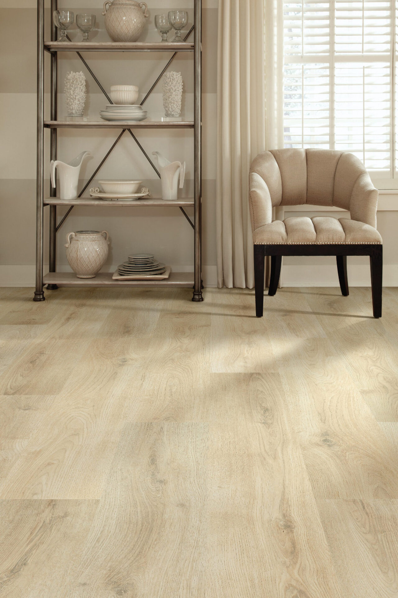 Light beige wood-look laminate flooring in a sunny room corner with shelving and an armchair