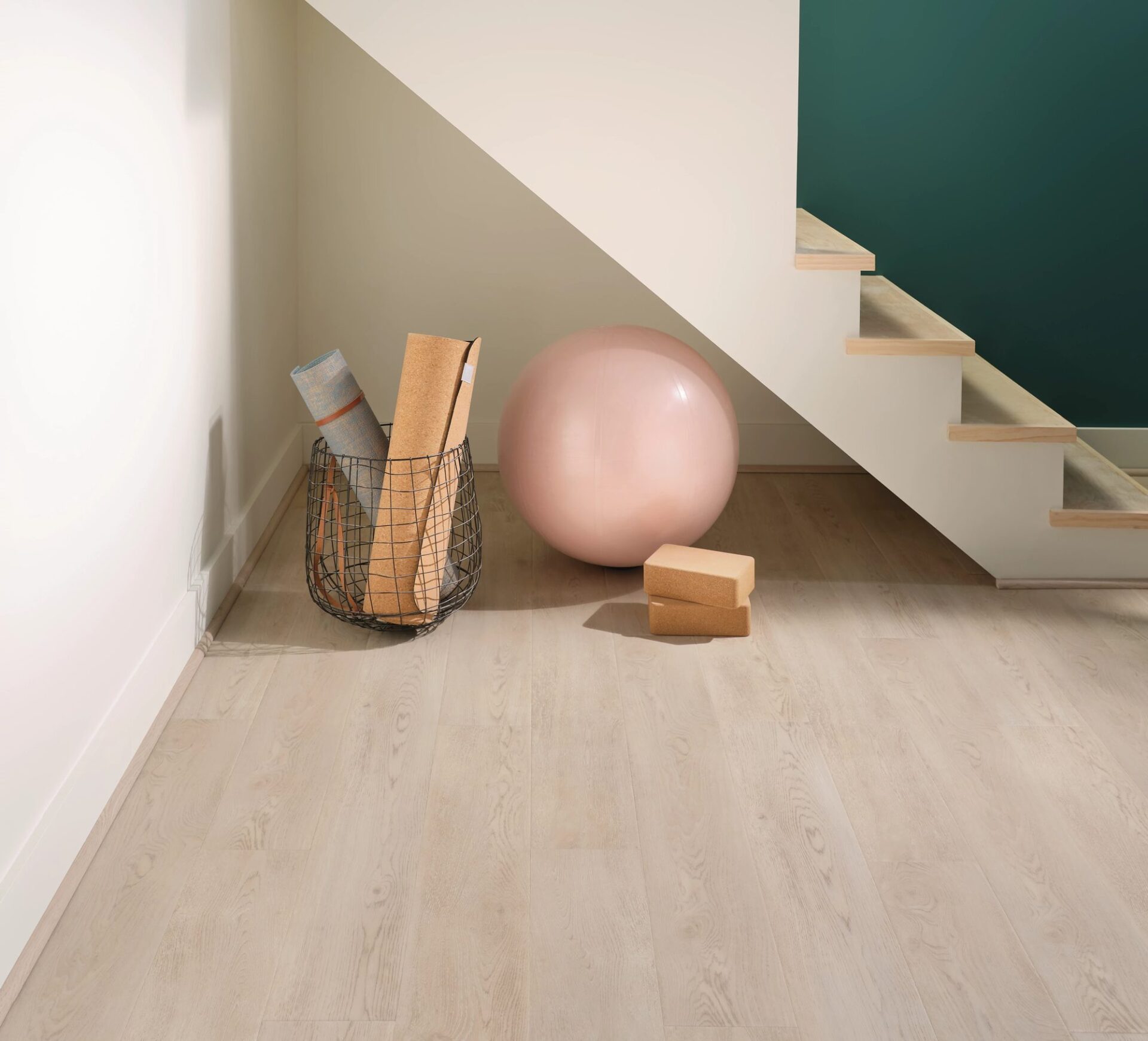 Pale oak look vinyl plank under a staircase with a yoga ball, blocks and a basket of mats