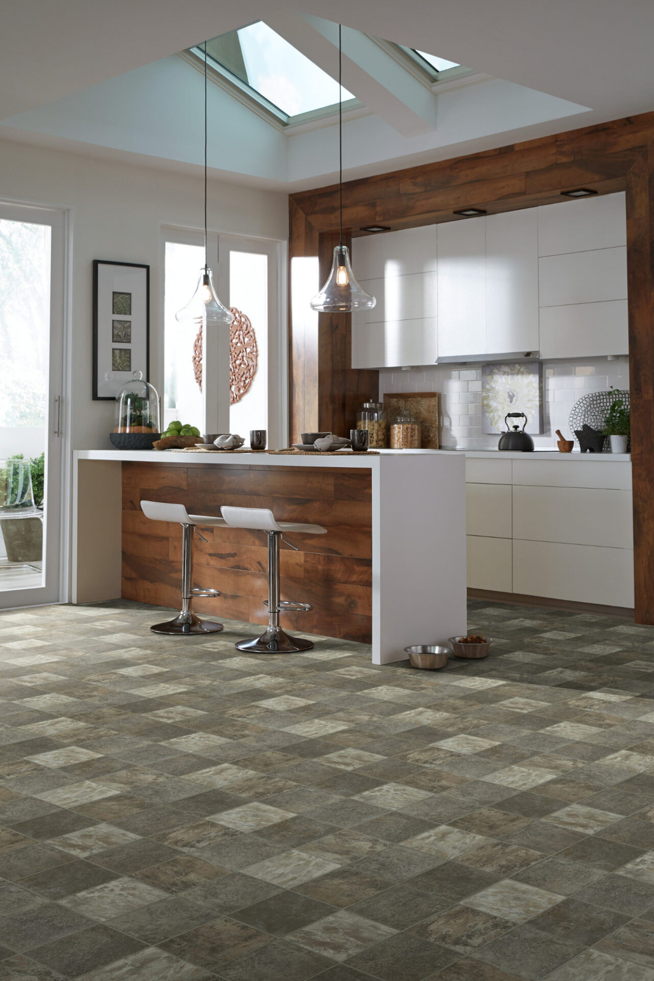 Gray patterned stone-look vinyl tile in a modern kitchen with a waterfall island and skylights