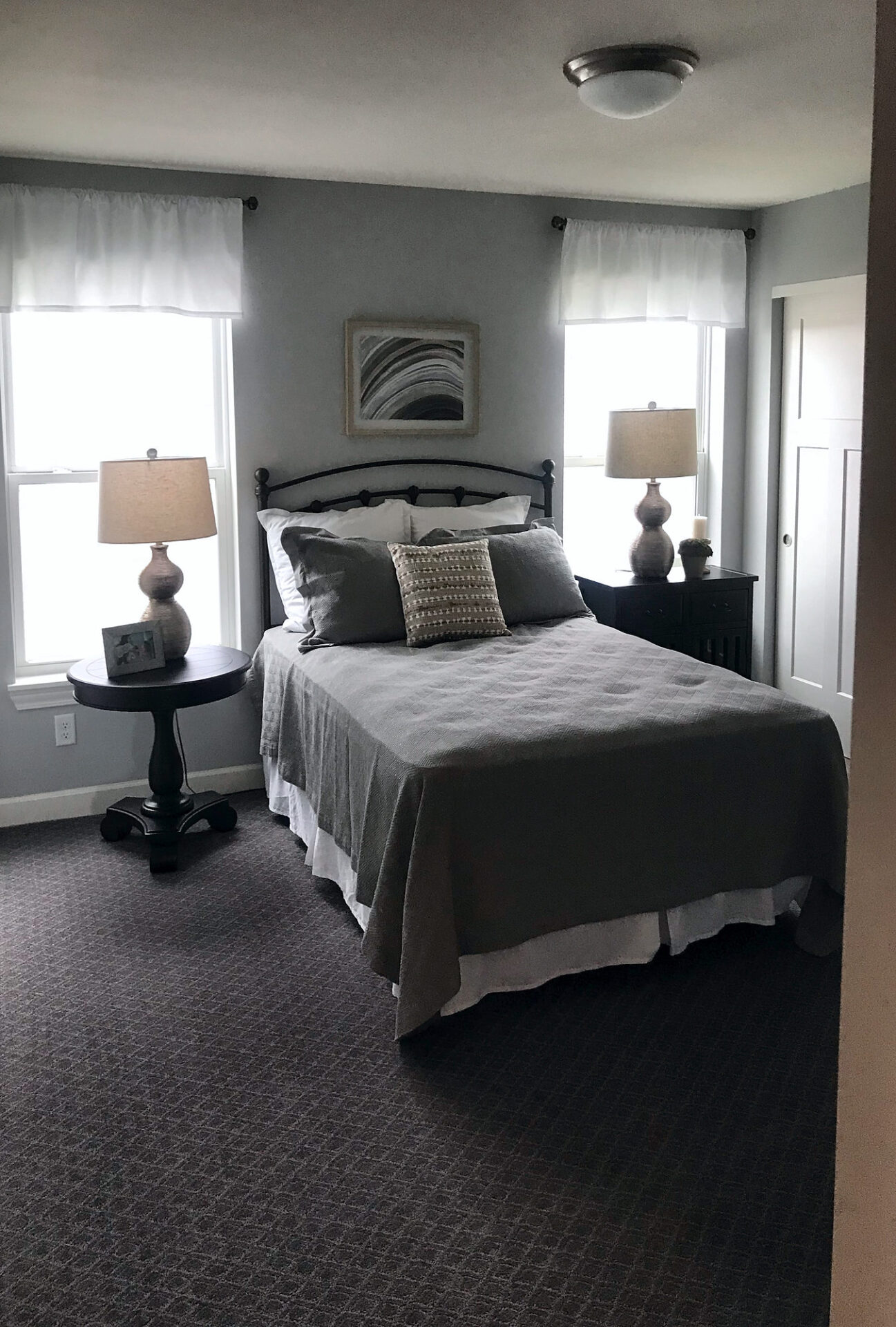 Patterned charcoal gray carpet in a staged bedroom with a metal bed frame and two windows