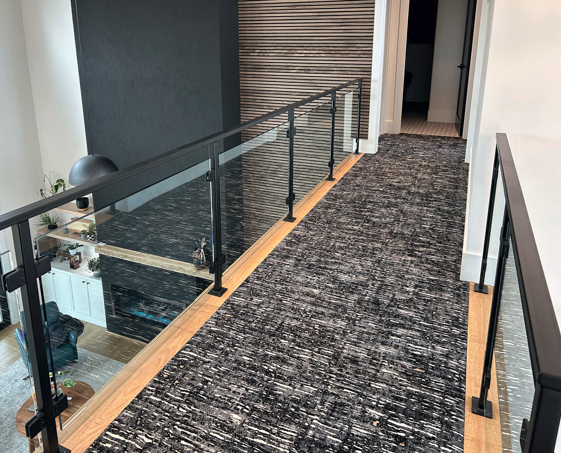 Black and white patterned carpet runner on a loft bridge with glass railings and oak edging