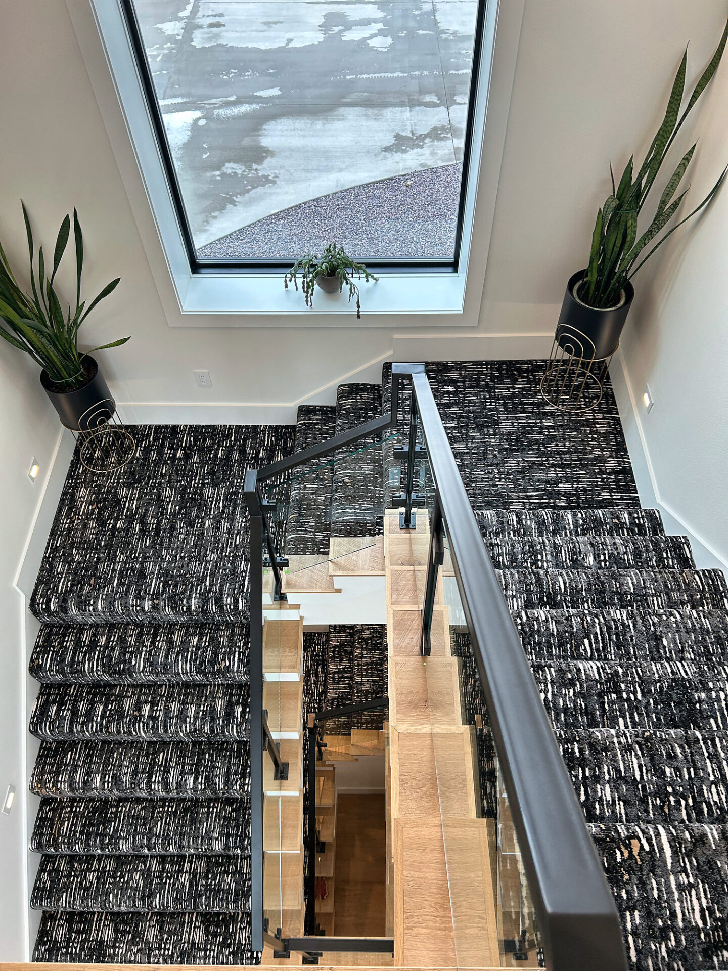 Split staircase with black and white patterned carpet treads and open oak stringers seen from above