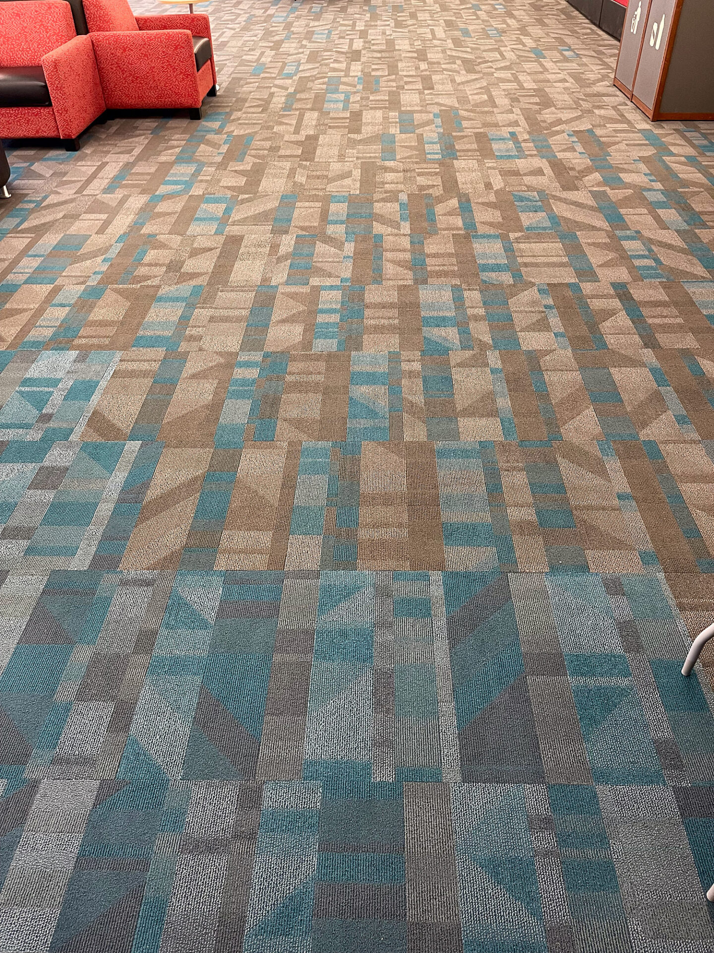 Close view of teal, tan and gray patterned commercial carpet tile in a student lounge
