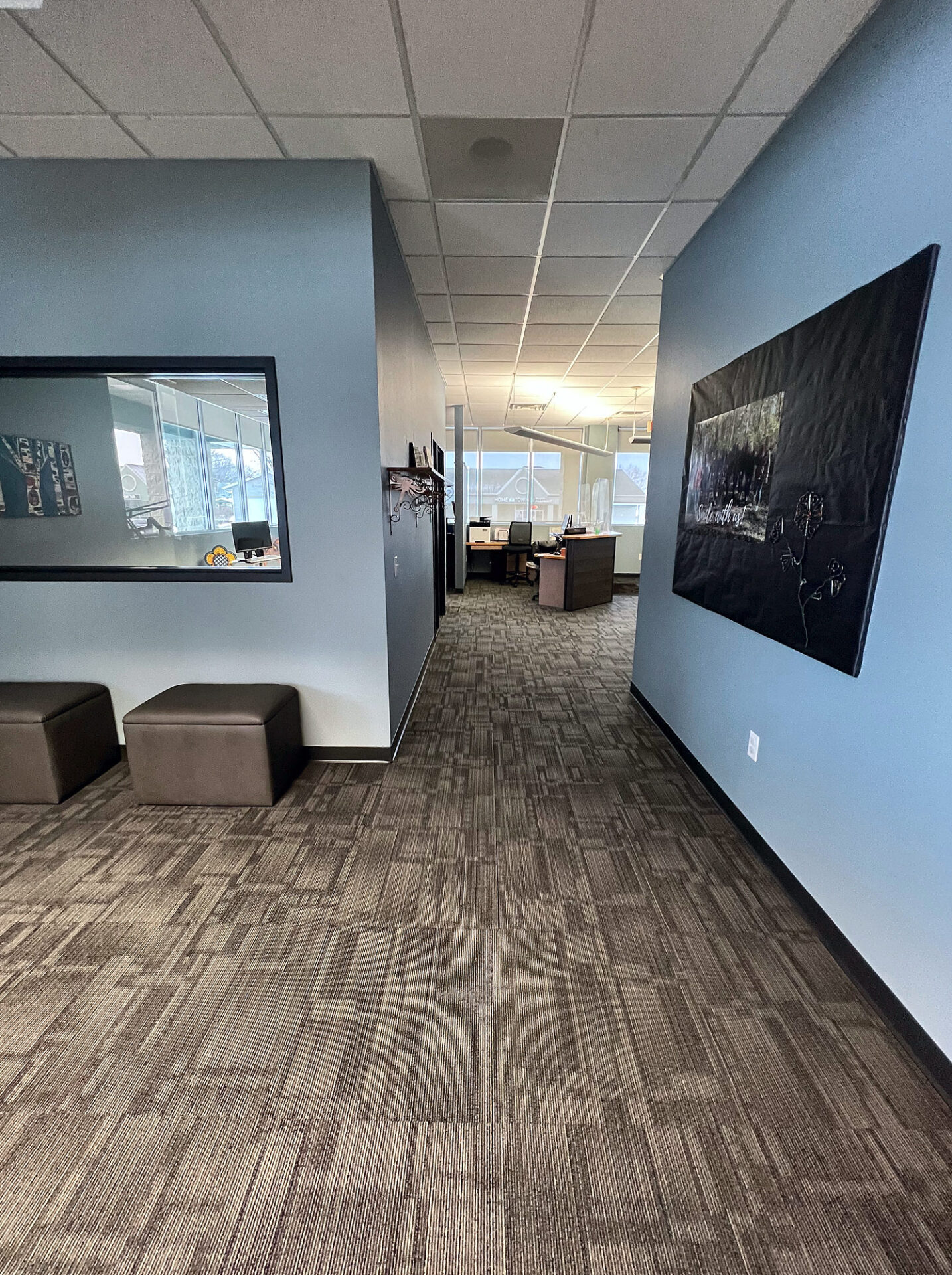 Brown and gray commercial carpet tile running down a clinic hallway with blue walls