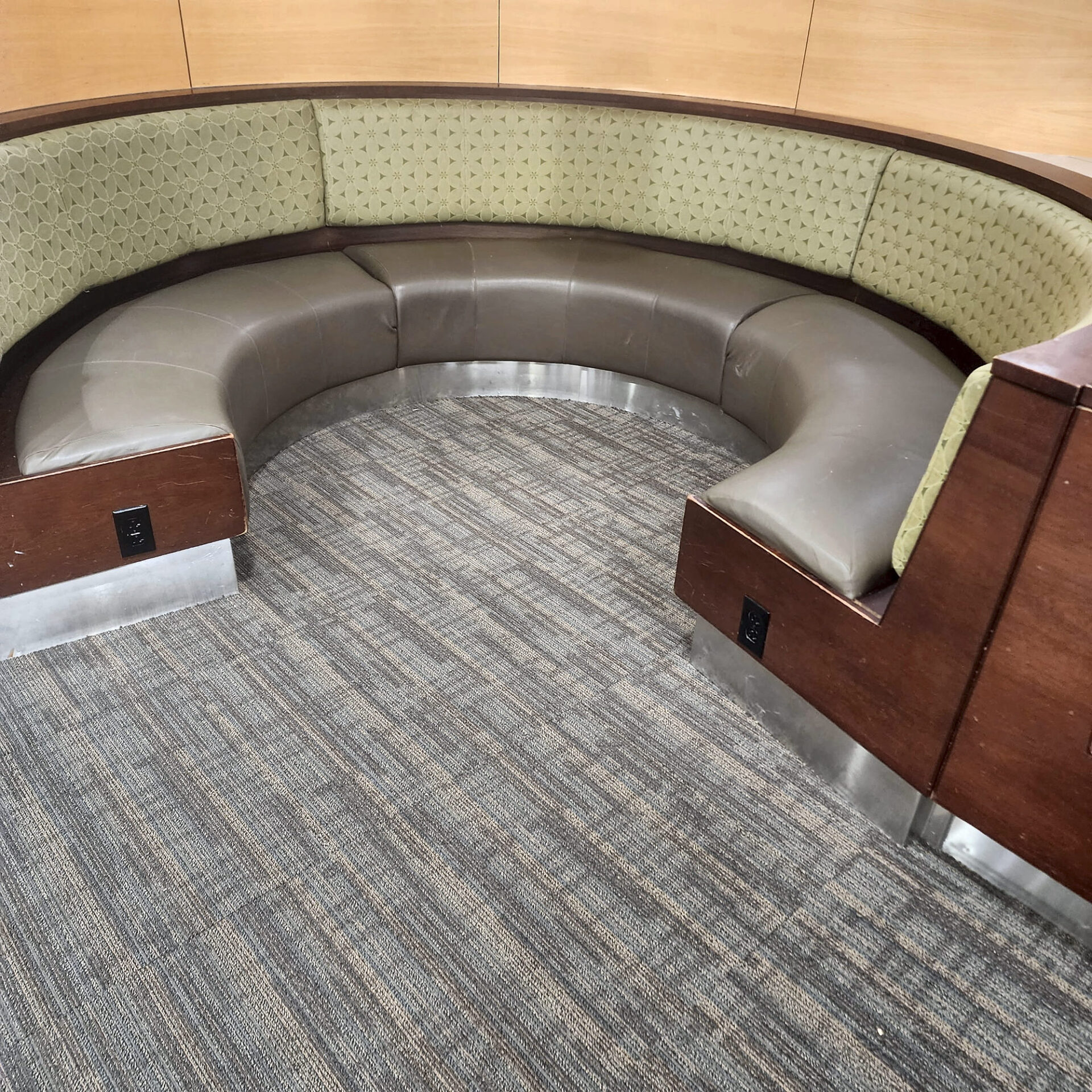 Brown and gray linear commercial carpet tile around a curved upholstered booth seat