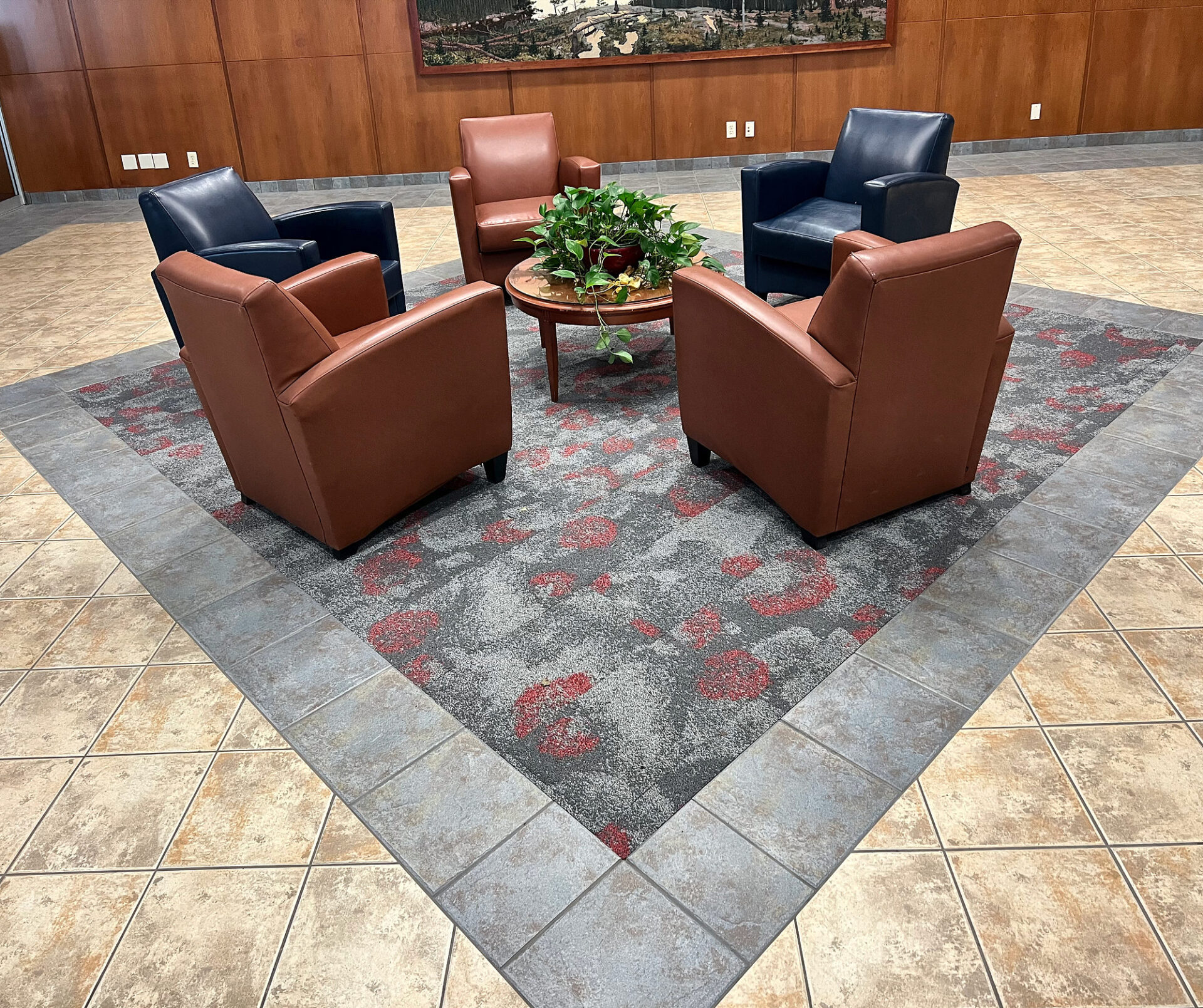 Beige porcelain tile lobby floor with a diagonal patterned carpet inset under a seating group