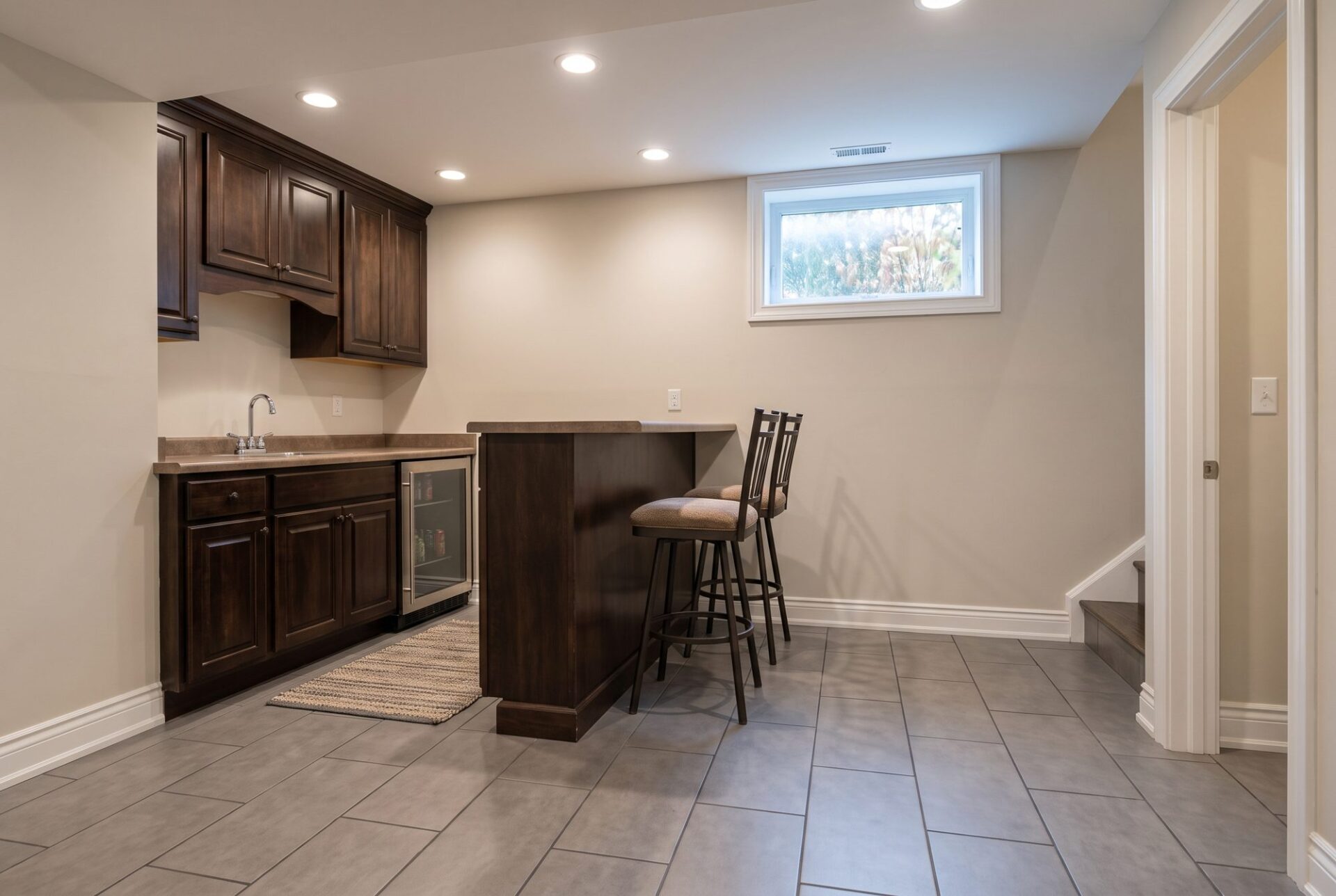 Gray concrete-look porcelain tile in an offset pattern at a finished basement wet bar