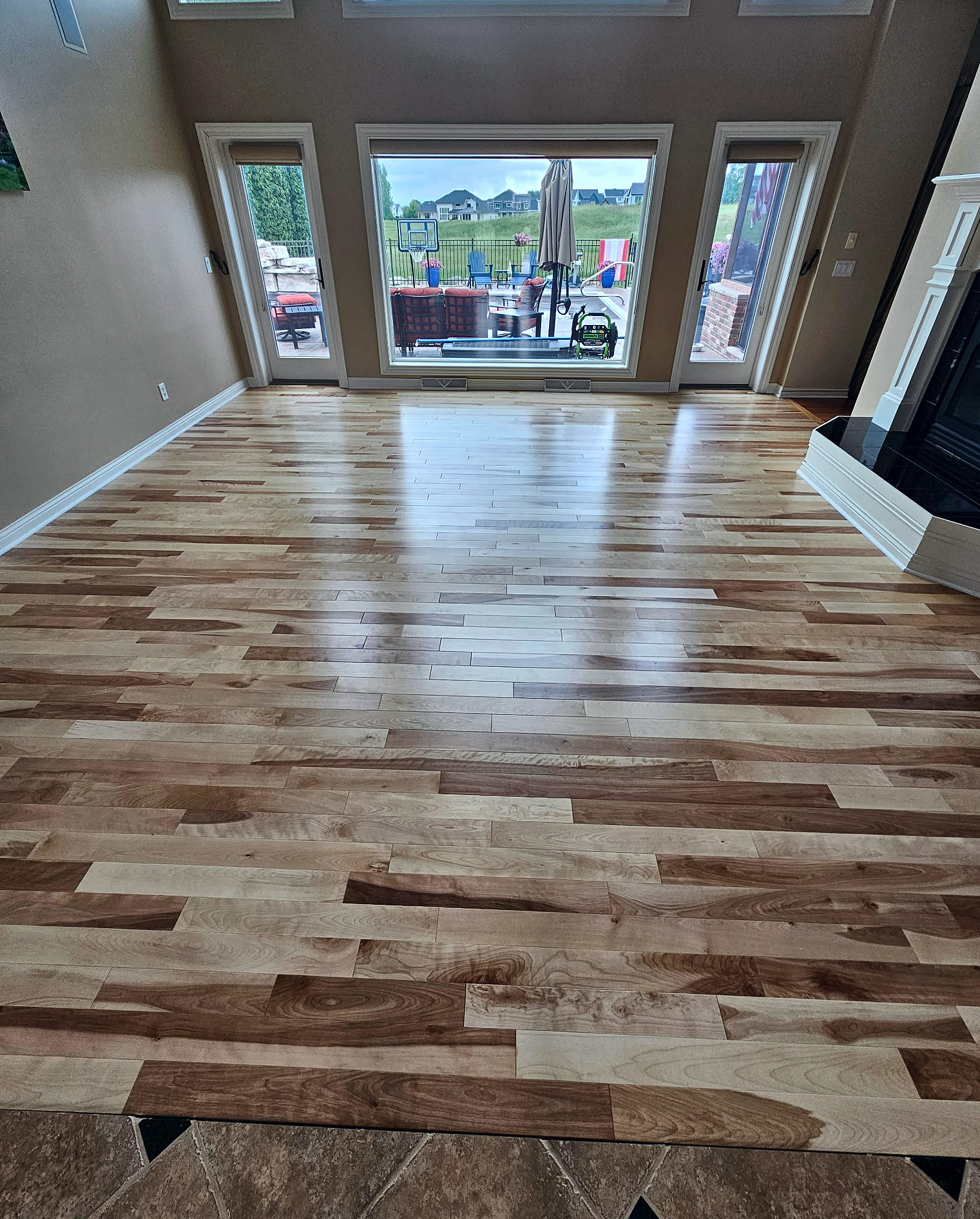 Natural hardwood floor with mixed light and dark boards in a bright two-story great room