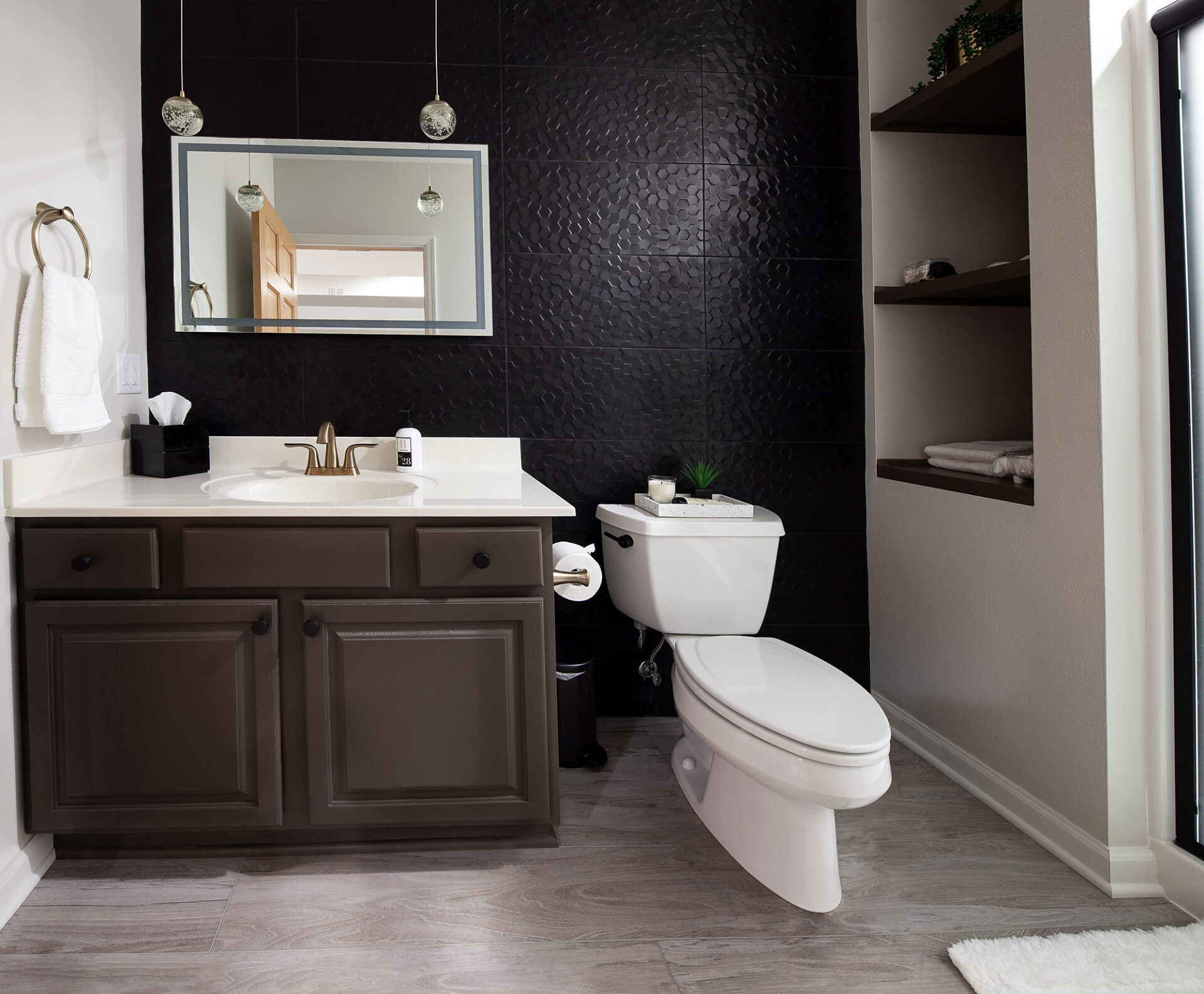 Light gray wood-look vinyl plank flooring in a bathroom with a dark tile accent wall