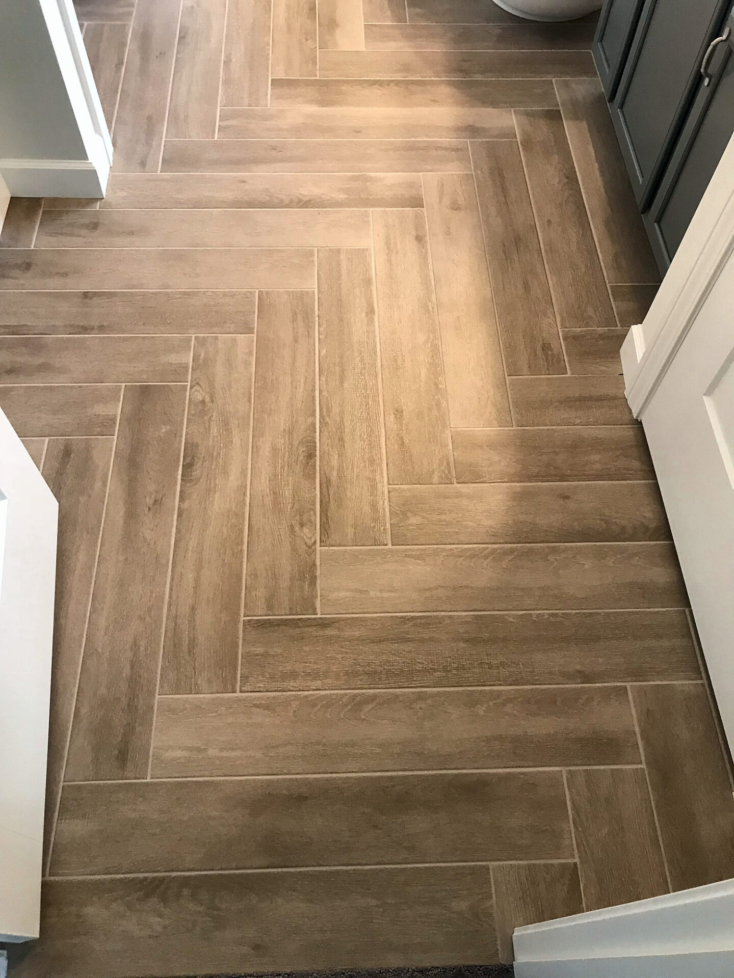 Overhead view of wood-look porcelain plank tile laid in a herringbone pattern in a bathroom