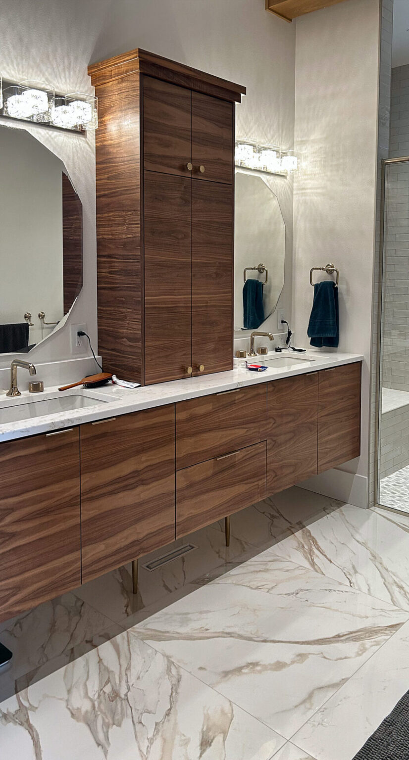 Large-format marble-look porcelain tile under a floating walnut vanity in a primary bathroom