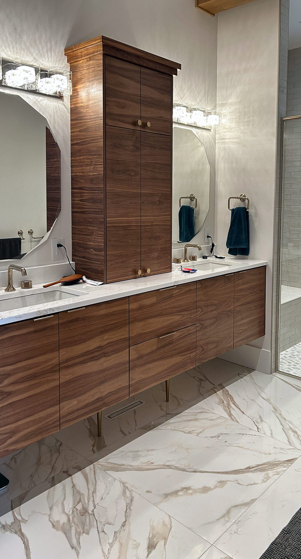 Large-format marble-look porcelain tile under a floating walnut vanity in a primary bathroom
