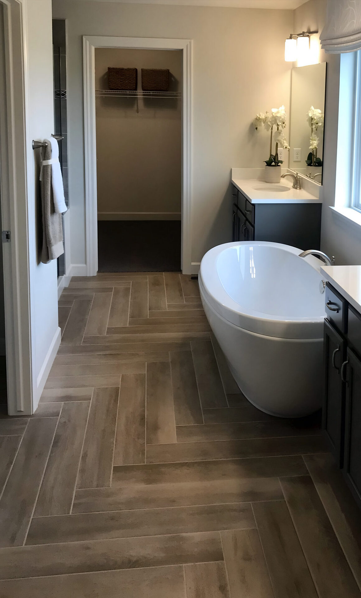 Wood-look porcelain tile laid in a herringbone pattern in a bathroom with a freestanding tub