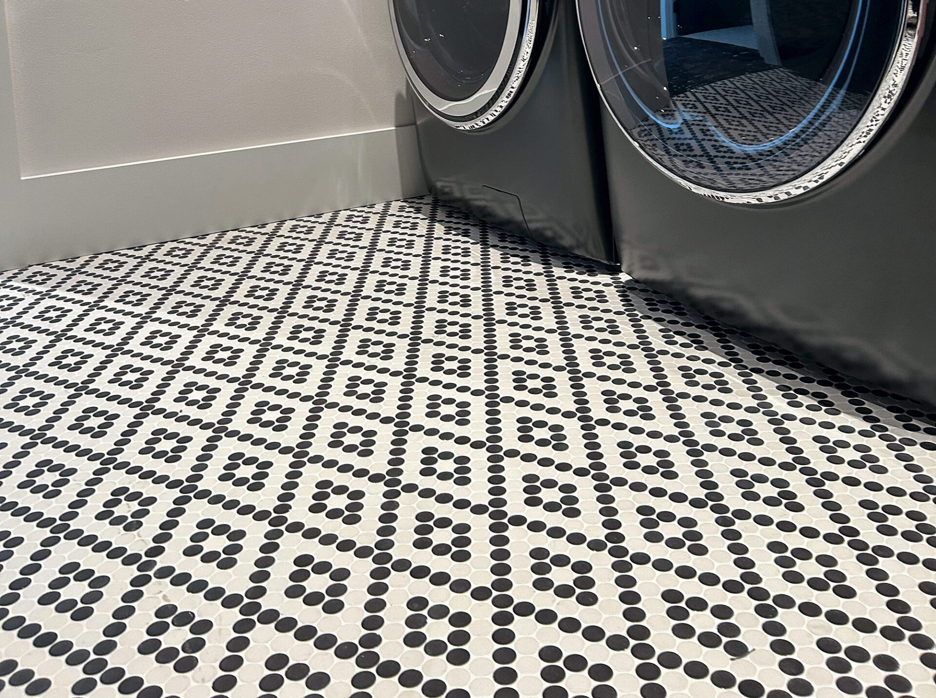 Black and white penny round mosaic tile in a geometric pattern on a laundry room floor