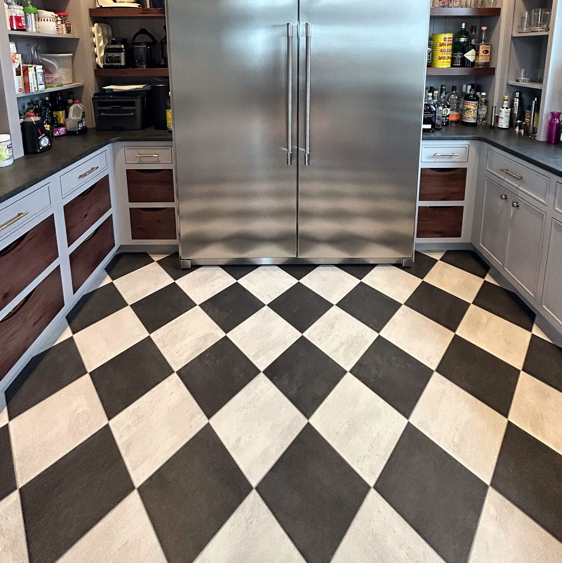 Black and white checkerboard tile floor in a walk-in pantry with a built-in refrigerator