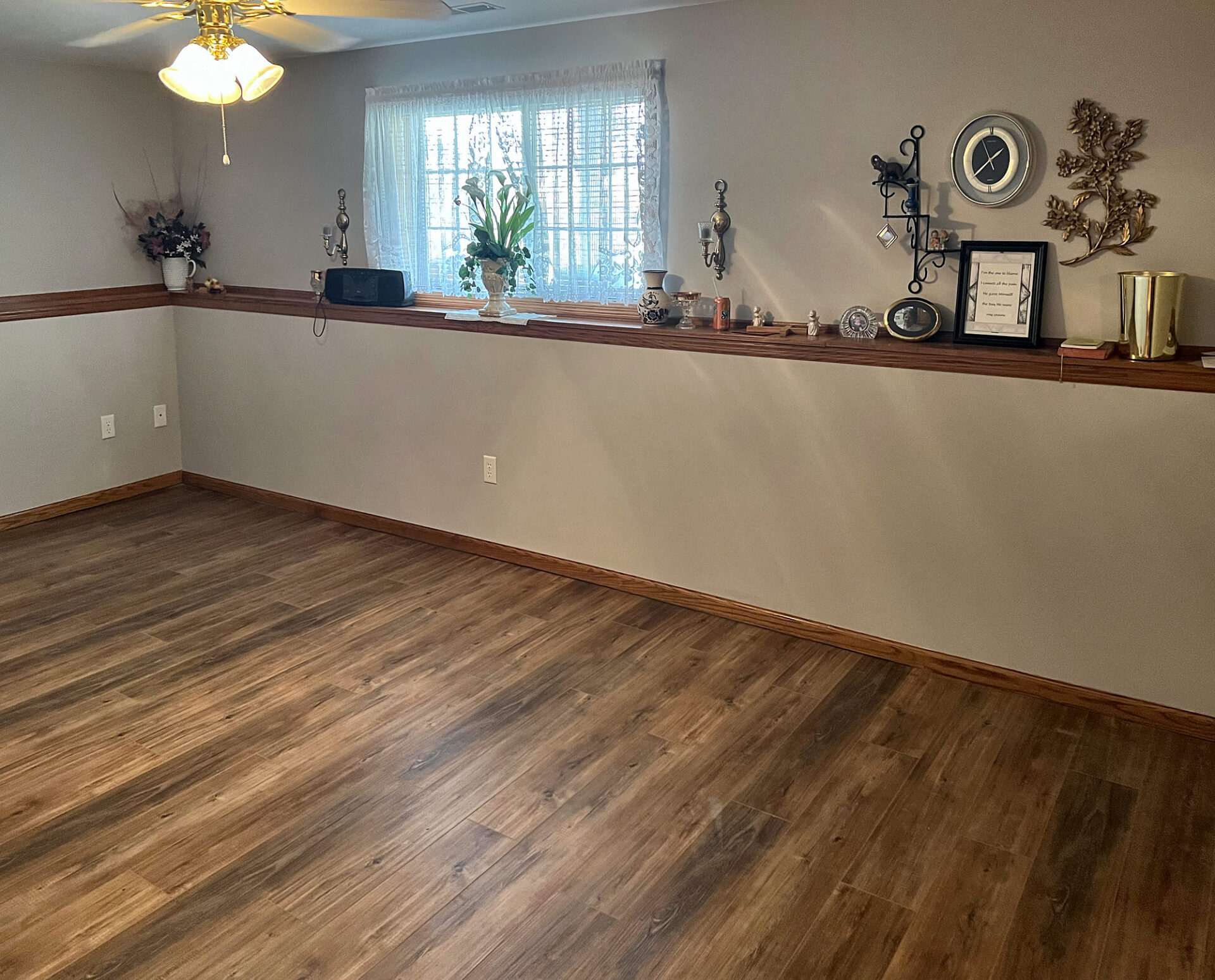 Brown wood-look vinyl plank flooring in an empty finished basement room with a window
