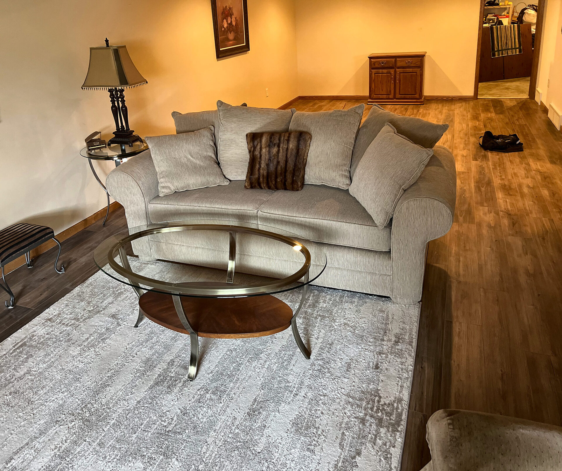 Brown wood-look vinyl plank flooring in a basement living area with a sofa and area rug