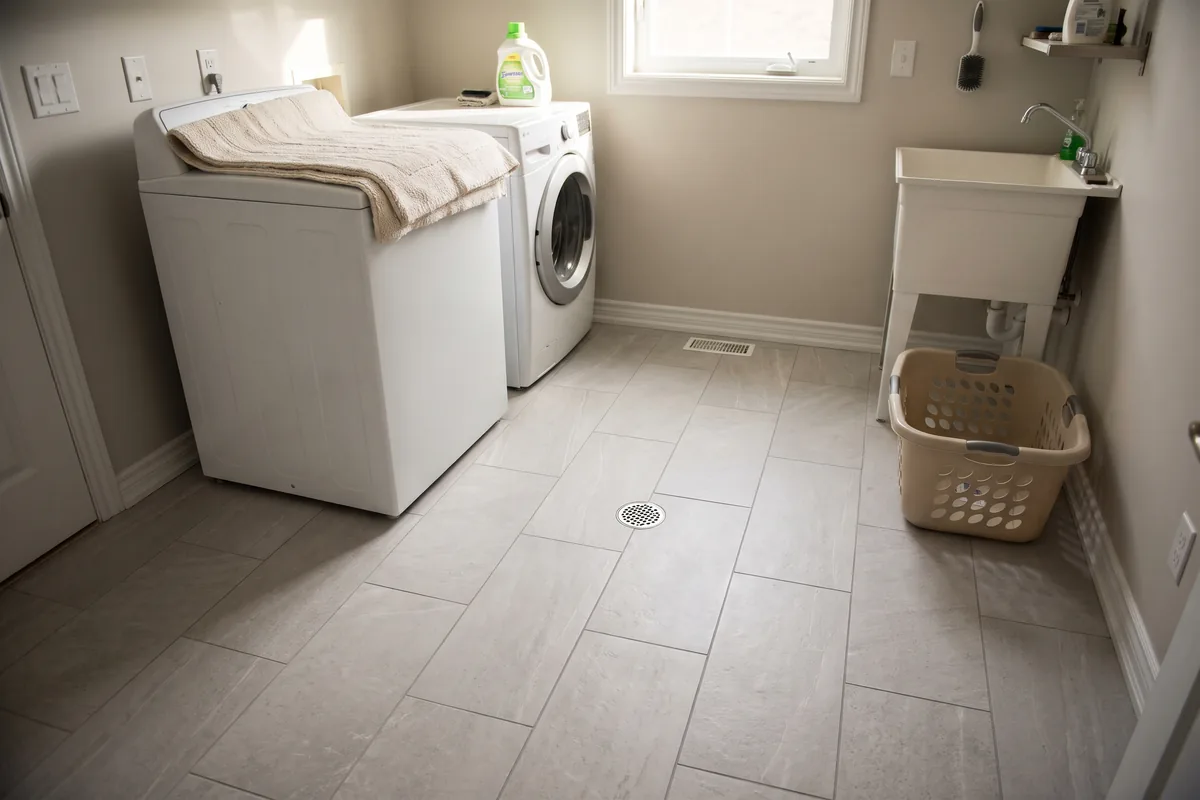 Light gray porcelain tile floor in a laundry room with a floor drain
