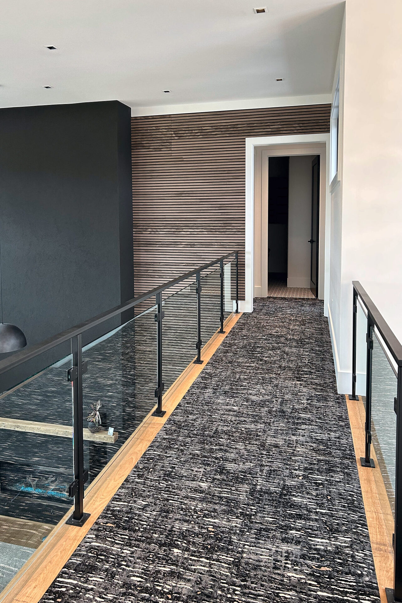 Patterned carpet runner down the center of a loft bridge with glass railings on both sides